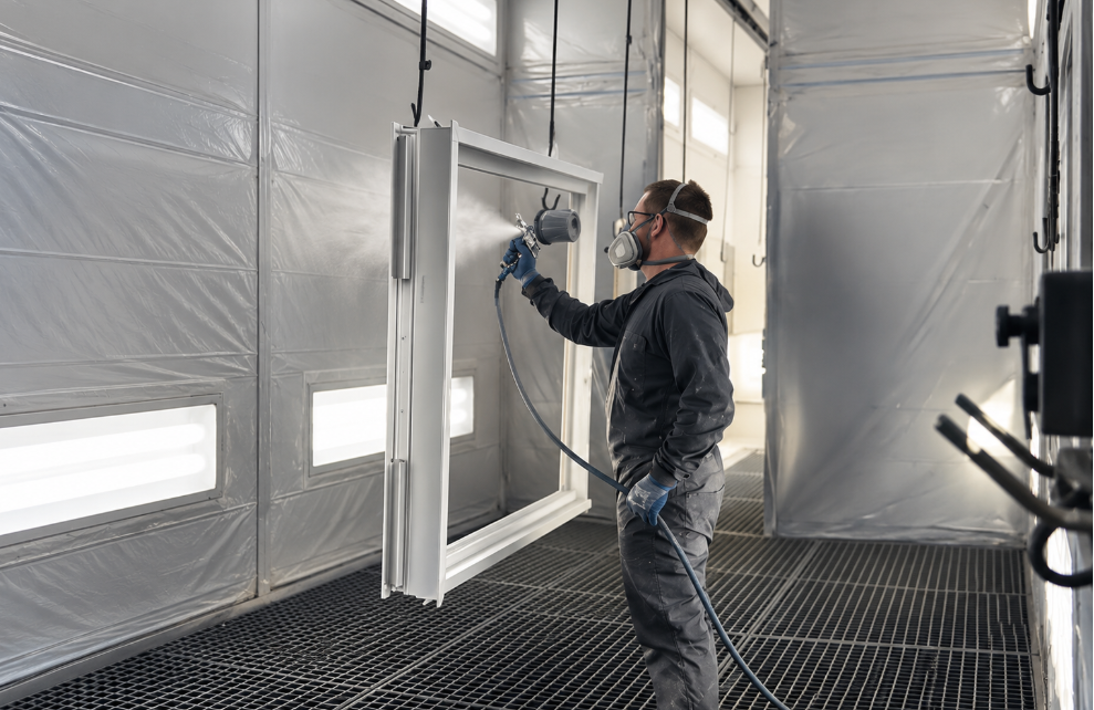 Technicien appliquant un laquage sur des profilés métalliques